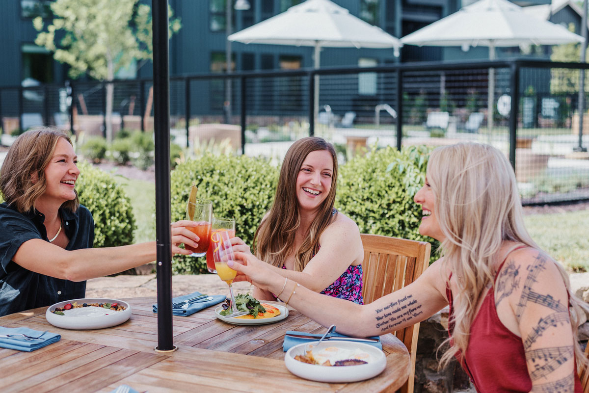 Group of women eating and drinking on patio at The Stonebreaker